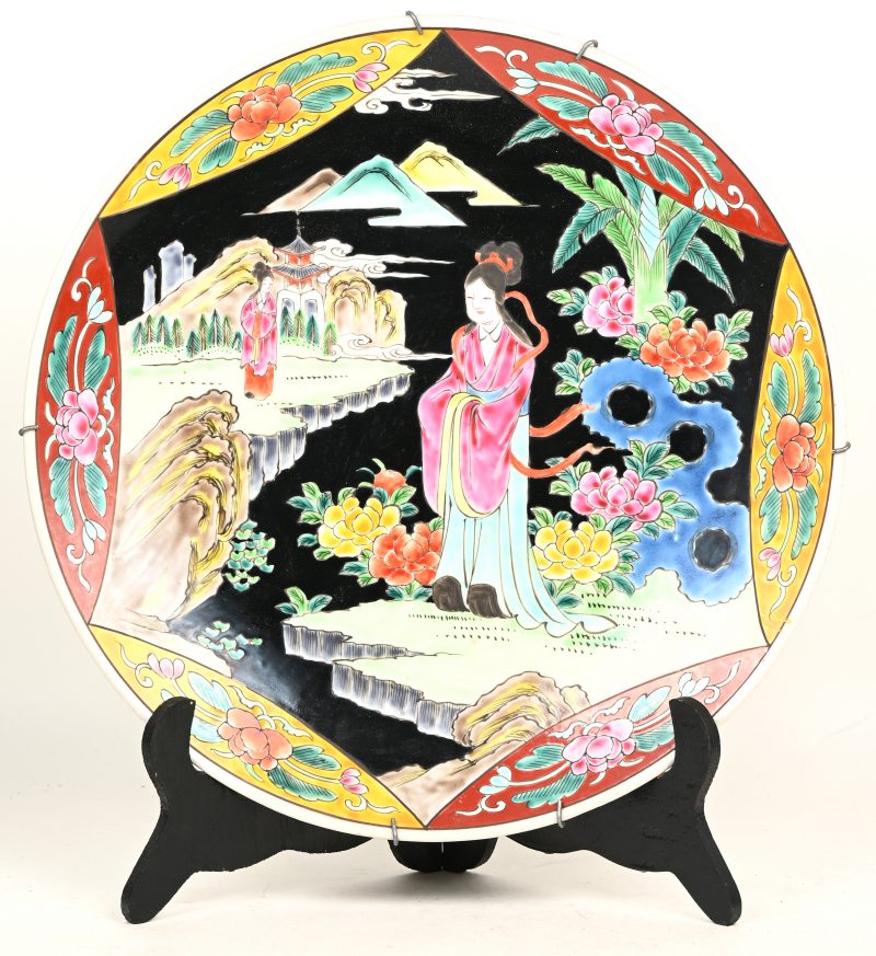 Een Chinees porseleinen bord, famille noir met figuren gedecoreerd.
