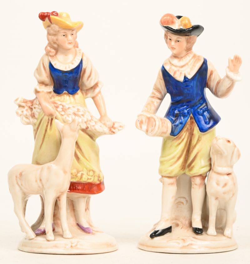 Een lot van twee Duits porseleinen beeldjes. Een herderin met lam en knecht met hond. Onderaan gemerkt