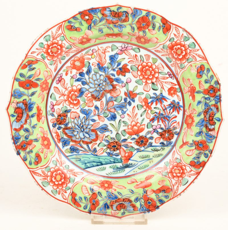 Een overgedecoreerd Chinees porseleinen bord met bloemdecor en vergulde accenten. Oude restauratie aan de rand. 18de eeuws.