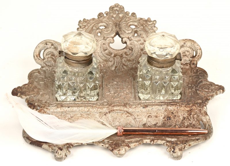 Een metalen inktpothouder met twee uit glas gesculptuurde inktpotjes en bijgevoegd modern pennetje met veer.