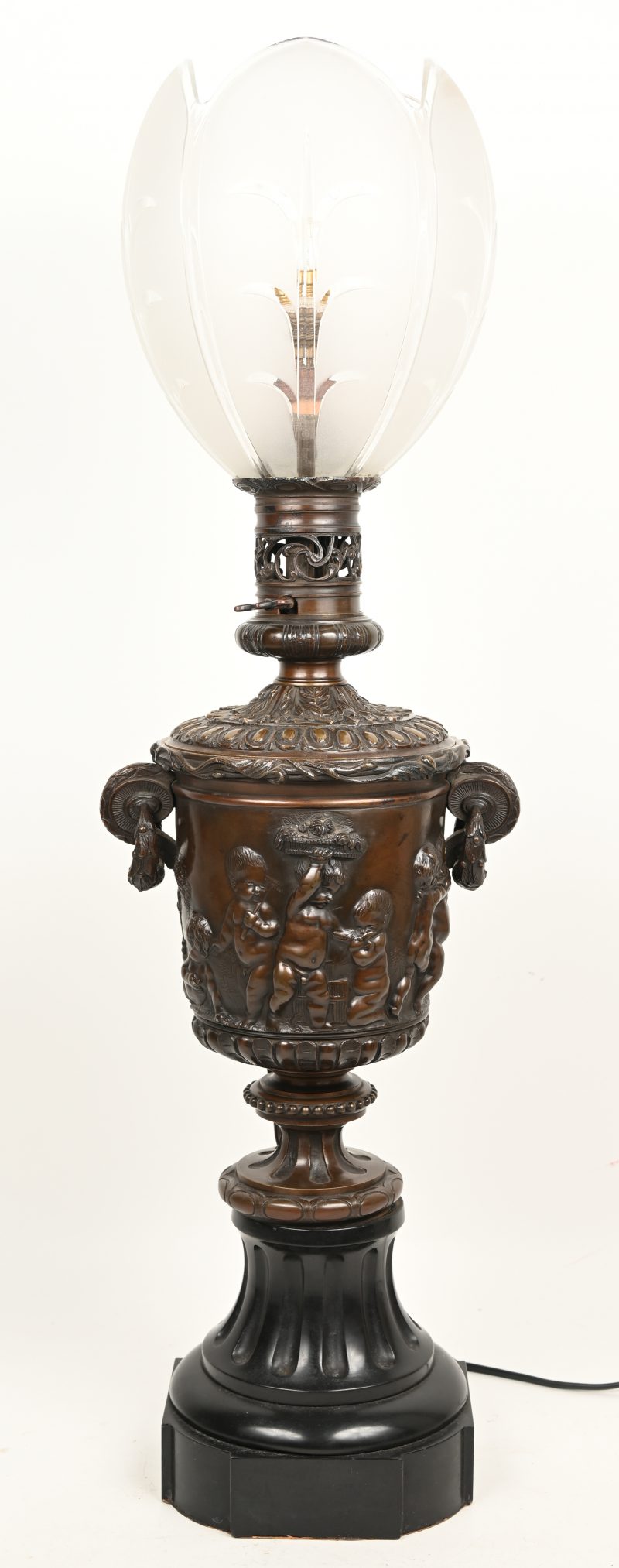 Een bronzen olielamp op arduinen voet met bacchanale voorstellingen. Met satijnglazen kap. Met lamp gemonteerd.
