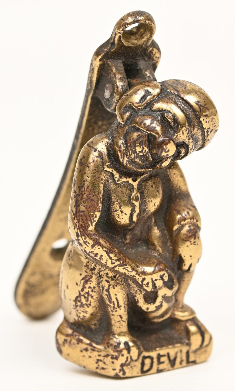 Een kleine bronzen deurklopper in de vorm van een zittende man met opschrift “Devil”. XIXde eeuw.