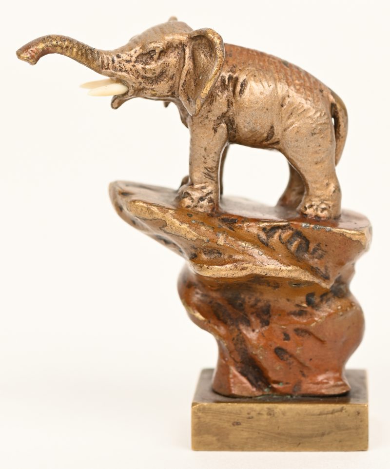 Een bronzen stempeltje in de vorm van een fijn uitgewerkte olifant op een rots. Met wapenschild.