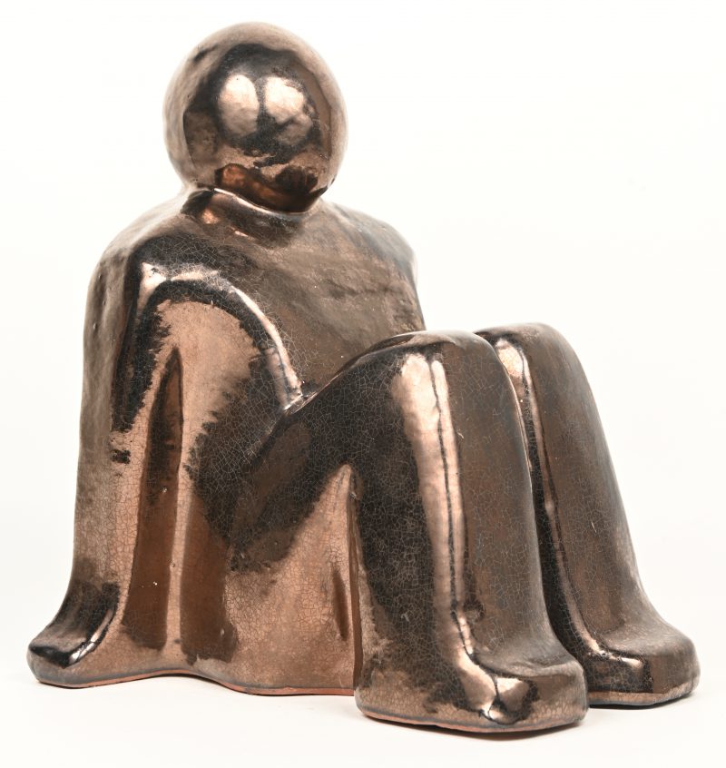 “Zithouding”. Een gestyleerd beeldje uit terracotta met craquellé glazuur van figuur in zithouding. Gemerkt onderaan, gedateerd 1980.