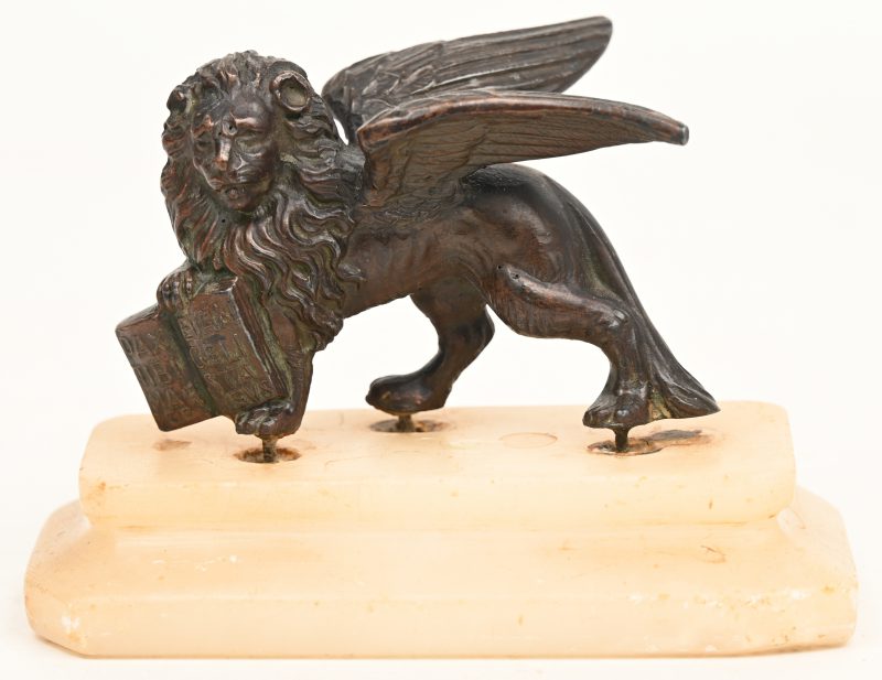 Een brons gesculptuurd beeldje van een gevleugelde leeuw met boek op marmeren voet. Naar de leeuw van San Marco.