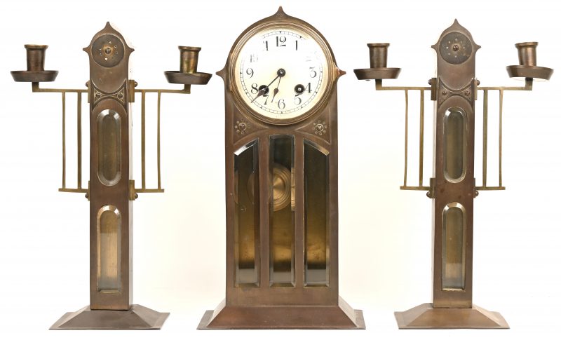 Een 3-delig koperen klokstel, bestaande uit klok en twee kandelaars met 2-lichtpunten. Vermoedelijk ontwerp Wiener Werkstätte, 1903-1932.