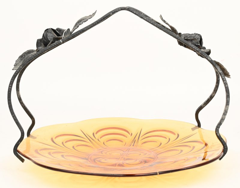 Een vintage schaal uit amberkleurig glas met smeedwerk.
