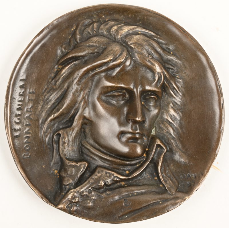 Een rond bronzen, gesculptuurde plaque met Napeleon hierop afgebeeld. Opschrift “Le General Bonaparte”.