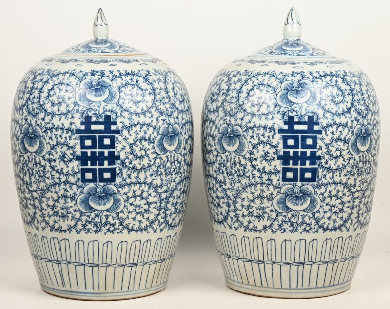 Een paar Chinees porseleinen gemberpotten, hoog, blauw-wit en versierd met flora in het decor.