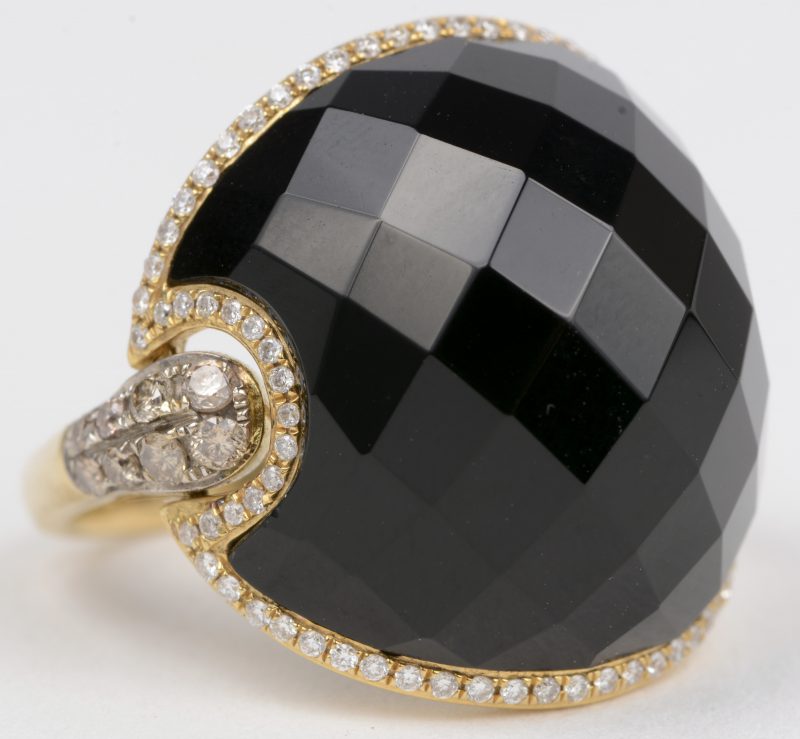 Een 18 K geelgouden ring bezet met twee kleuren briljanten en met een gezamenlijk gewicht van +- 1 ct. en onyx.