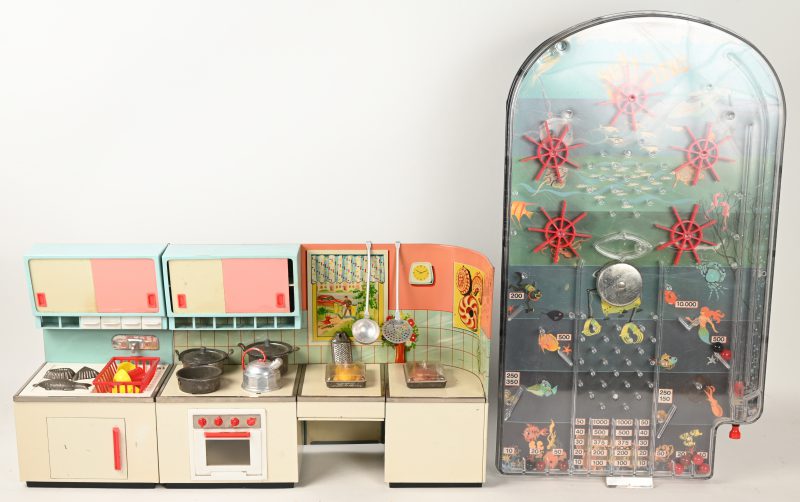 Een blikken speelgoedkeukentje en een plastic flipperspel.