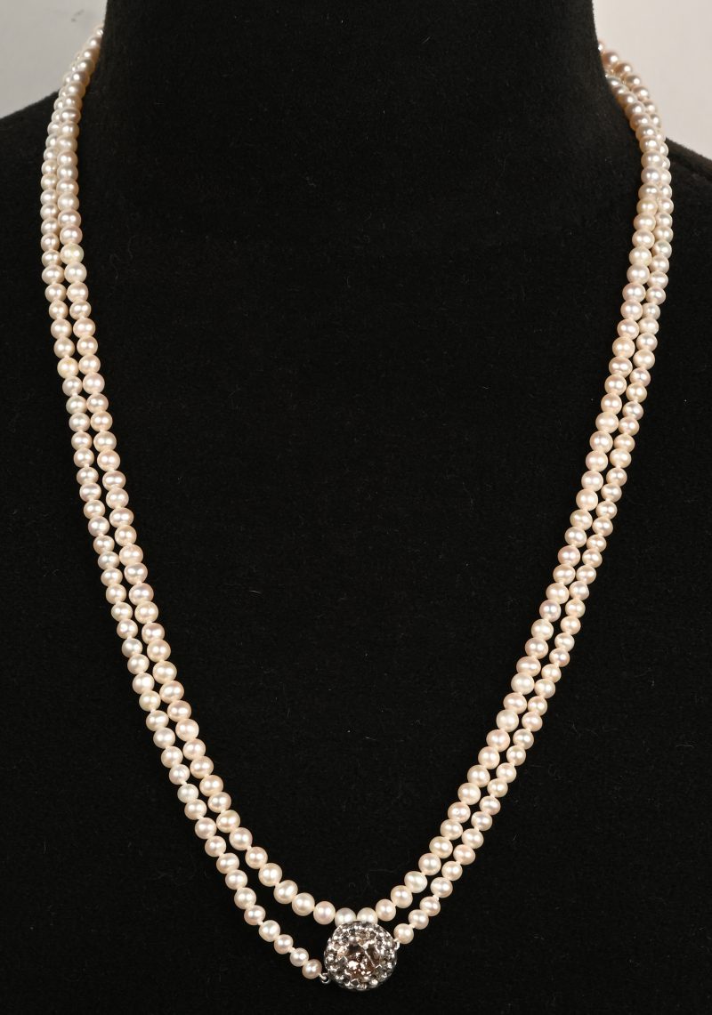 Een lange parelhalssnoer bezet met één cognackleurige diamant princess cut in zilver gezet met een gezamenlijk gewicht van +- 0,70 ct.