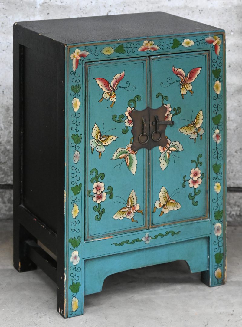 Een klein tweedeurskastje met vooraan gelakte versiering van vlinders en bloemen. Chinees werk.