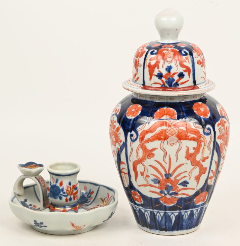 Een lot Imari porselein bestaande uit een vaas met deksel en divers decor versierd en kaarsenhouden.