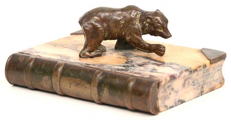 Een uit marmer gesculptuurd boekje met bronzen beeldje van een beer.