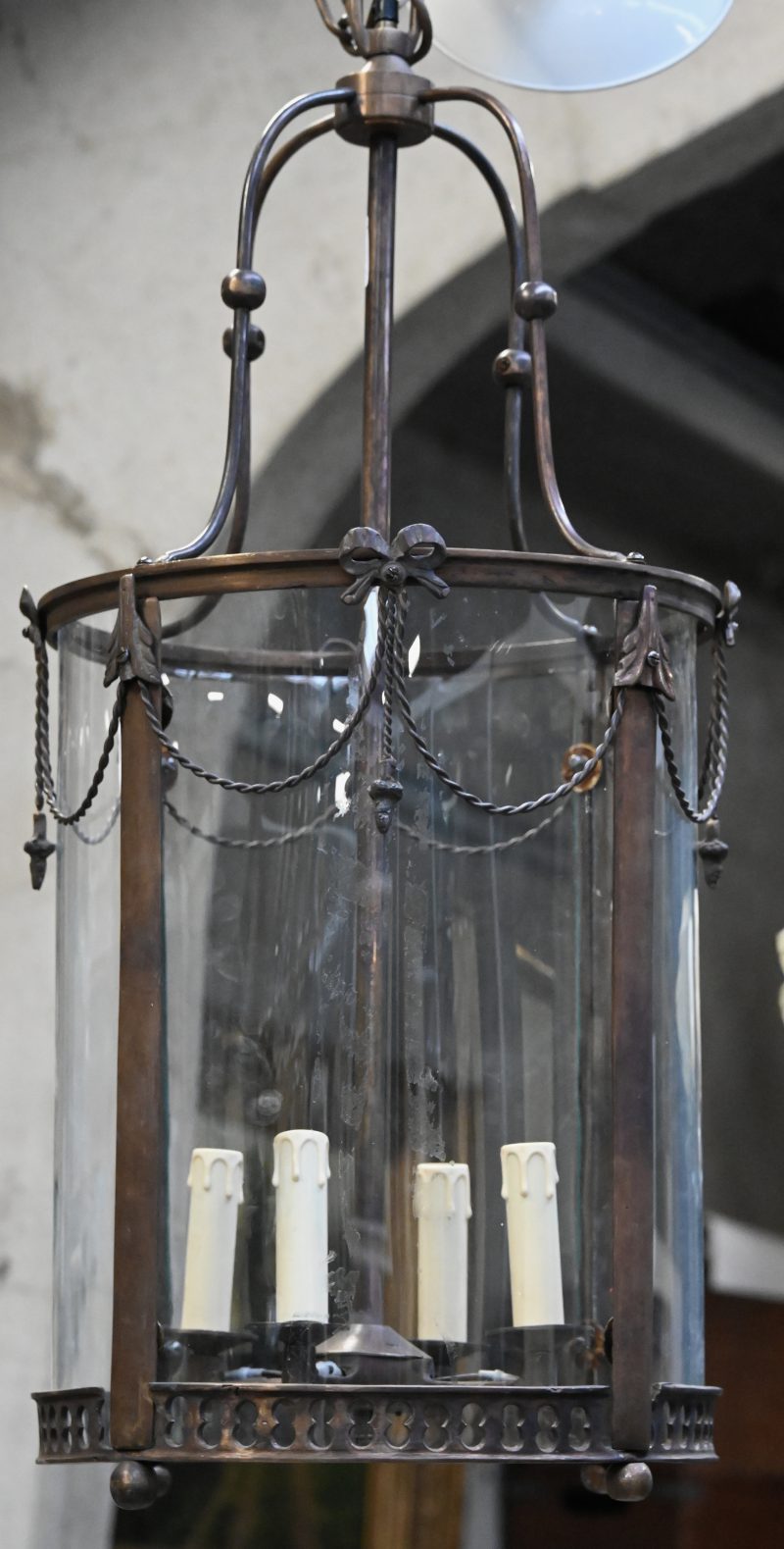 Een cilindervormige hallantaarn in Louis XVI stijl met bronzen frame en 4 lichtpunten.