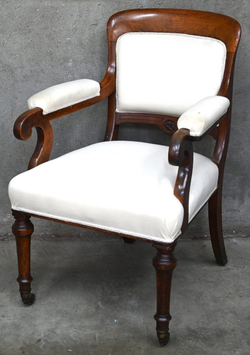 Een Engels eiken houten stoel met armleuning, wieltjes en witte stoffering.