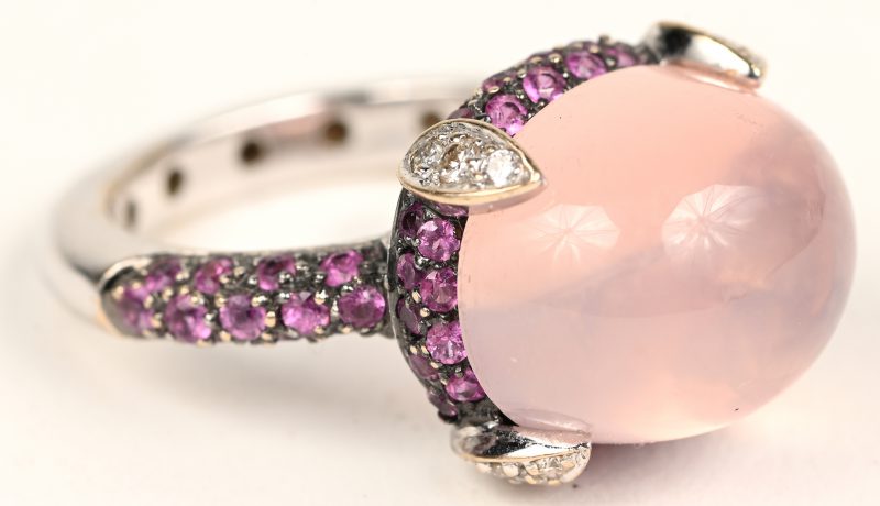 Een 18 karaats witgouden ring bezet met briljanten en roze saffieren met een gezamenlijk gewicht van +- 1 ct. en een roze kwarts cabochon van +- 10 ct.