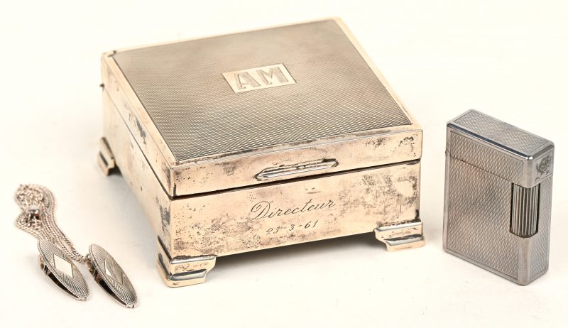 Een zilveren sigarettendoos, gemerkt 935/1000 met monogram A.M. en een Dupont aansteker, evelans een zilveren kettinkje met klips.