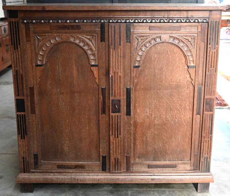 Een eikenhouten meubel met gesculpteerde versieringen in en rond de twee deuren.