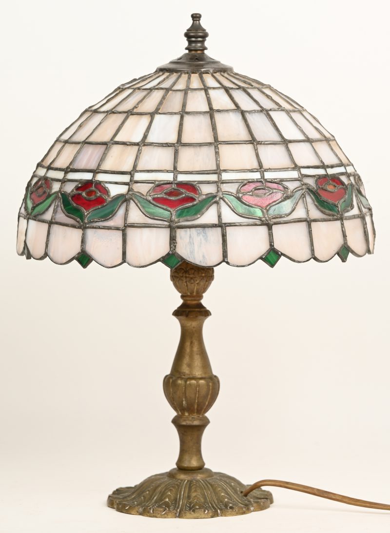 Een Tiffany tafellamp met een rozen-decor op de kap en bronzen voetje .