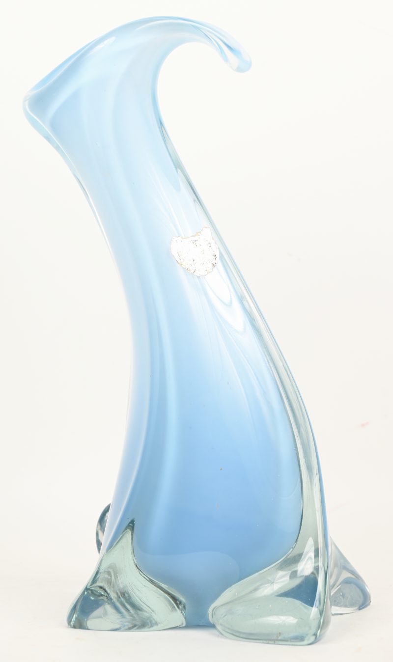 Een moderne vaas van gegoten kristal, licht blauw in de massa. Een schilfer onderaan de voet, en een barst aan de bovenrand.