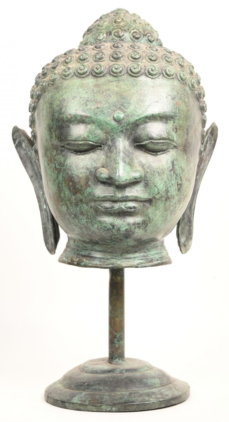 Een buddha hoofd op sokkel in koper .