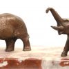Een vide-poche van wit en rood marmer met twee kleine bronzen olifantjes