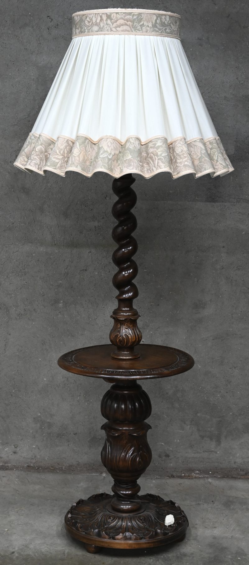 Een staande lamp met tafelblad en houten getorste voet.