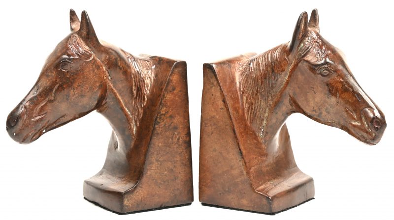 Een paar gepatineerd terracotta boeksteunen in de vorm van paardenhoofden.