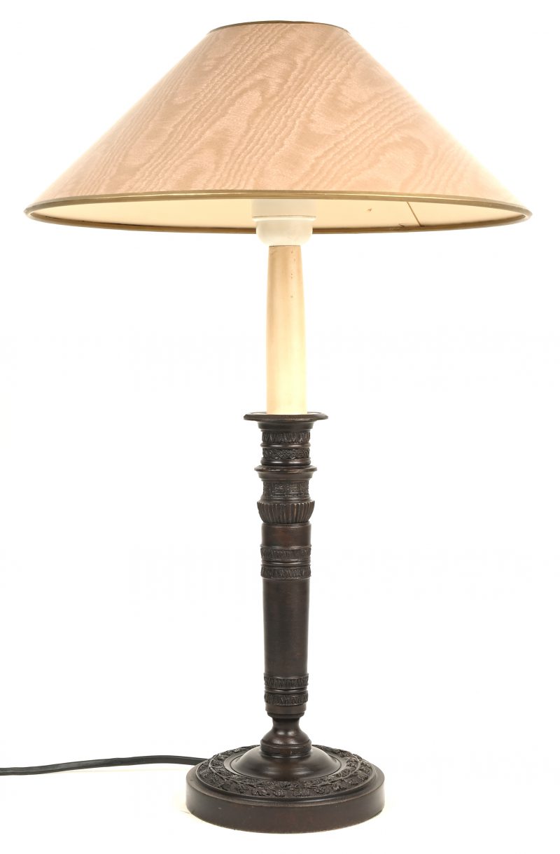 Een tafellamp uit kunstbrons met gesculpteerde details en kap.