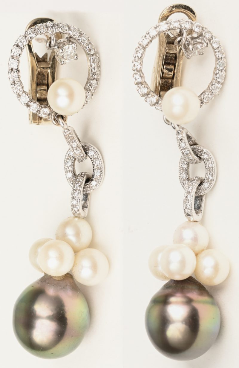 Een paar 18 karaats witgouden oorbellen bezet met briljanten met een gezamenlijk gewicht van +- 0,60 ct. en 10 kleine witte en 2 grote grijze parels.