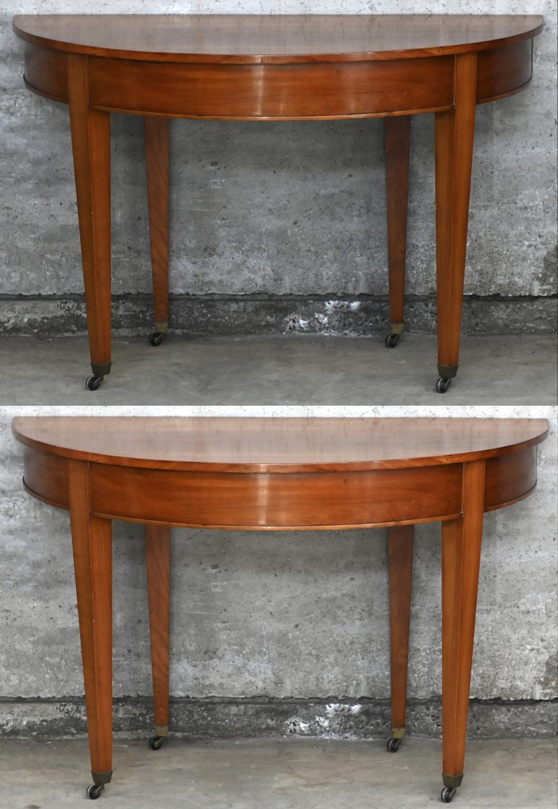 Een houten D-end tafel met rond blad bestaande uit 2 halve consoletafels met telkens 4 poten op wieltjes.