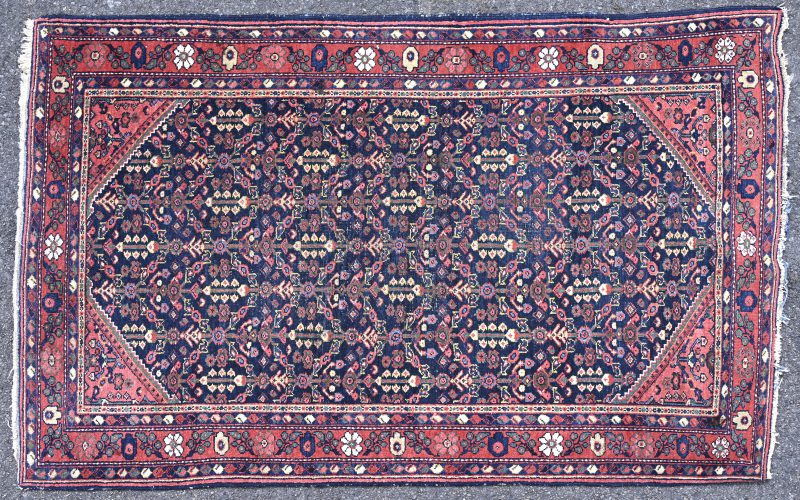 Een Perzisch wollen tapijt met sporen van slijtage.