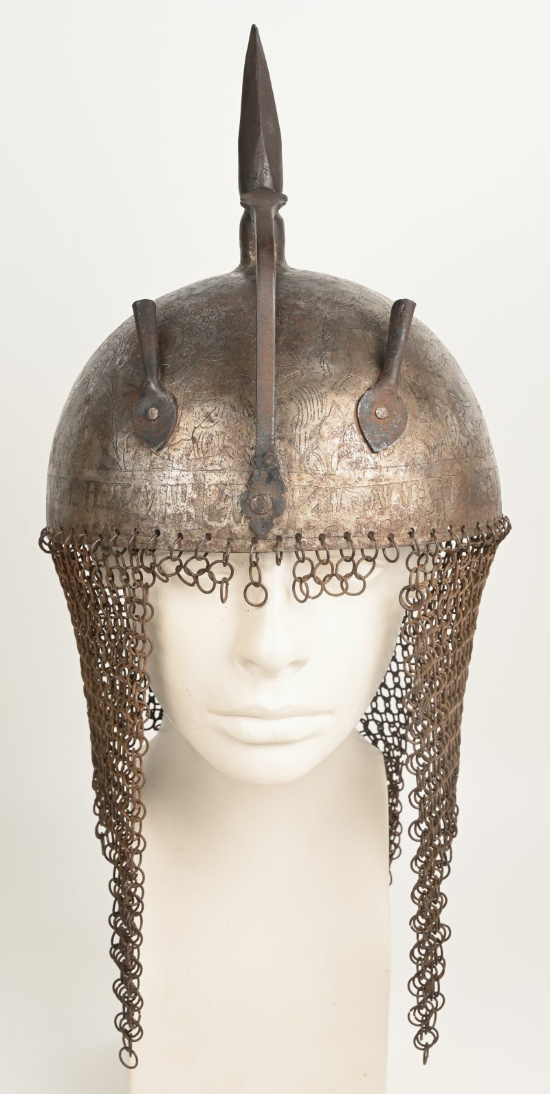 Een Perzische Kulah Khud helm met een gedamasceerd en geciseleerd decor versierd. Boven op de bolle helm een vierhoekige punt en twee aigrettehouders en achteraan een maliënlap. XIXde eeuw.