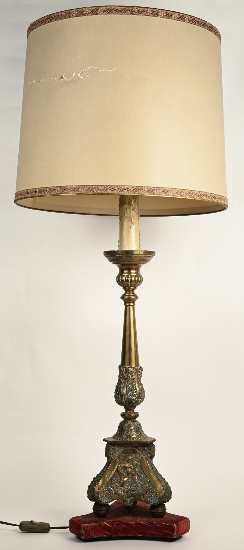 Een koperen lampadaire met kap.