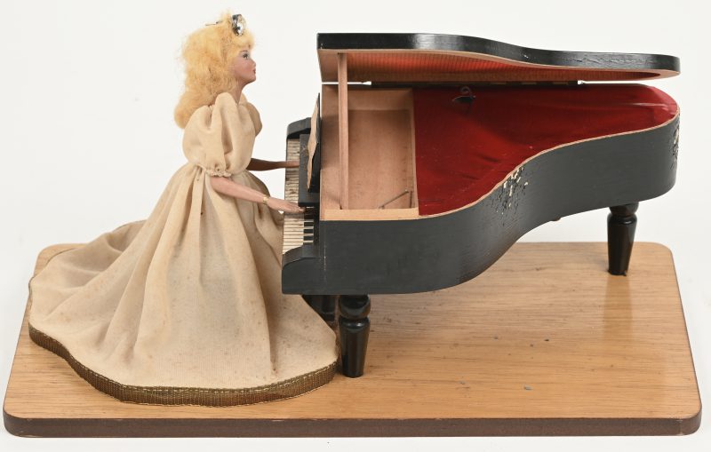 Een vintage muziekdoos, met porseleinen pop aan vleugelpiano.
