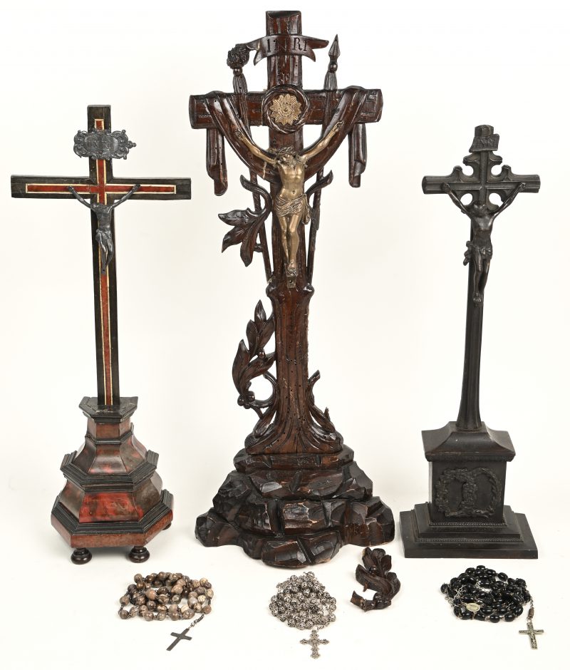 Een lot bestaande uit drie kruisbeelden, waarvan twee van hout en één van metaal, en drie paternosters. Eén zwaar beschadigd aan het hout en crucifix. De andere beschadigd aan het fineer, met oude herstellingen.