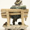 Een Capodimonte porseleinen beeldje van een landloper op een bankje. Restauratieschade thv het bankje.