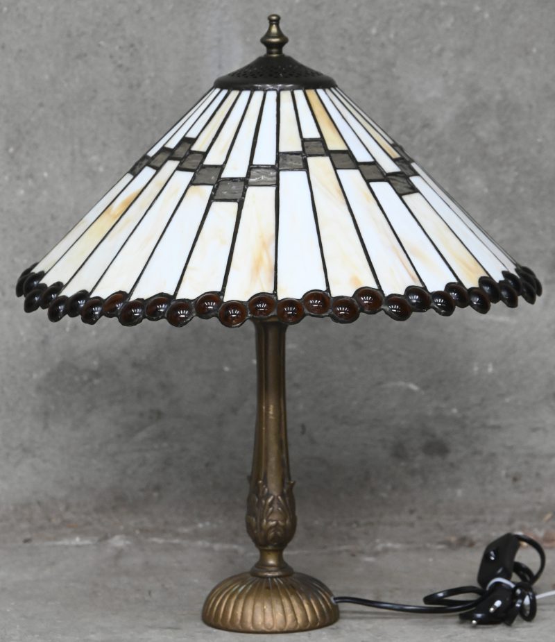Een Tiffany tafellamp met parelrand op een koperen voet.