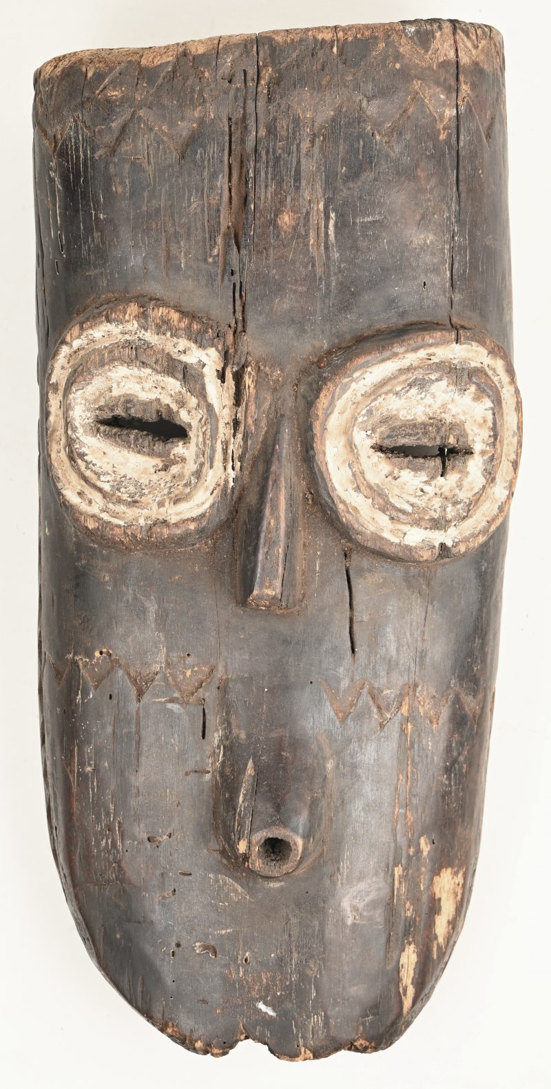 Een hout gesculptuurd Afrikaans masker met polychrome toetsen. Bembe, DRC.