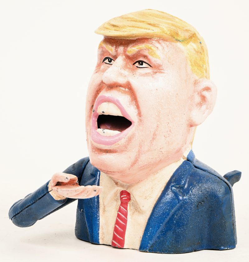 “Donald Trump”. Een aardewerken beeldje dat hand naar mond brengt, met opschrift achteraan “Make America Great Again”.