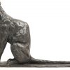 Een bronzen beeld van een gezeten panter in de verte starend.