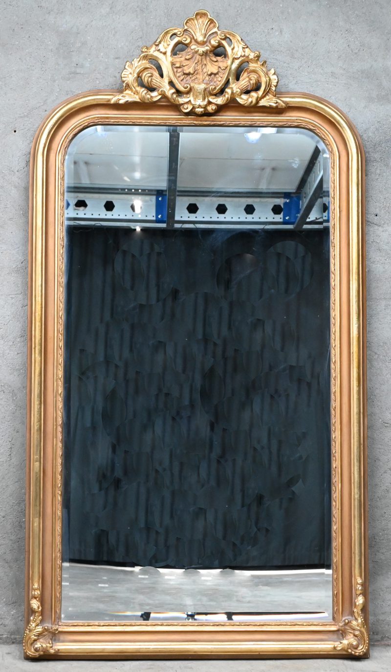 Een grote geslepen spiegel met vergulde kader en kuif.