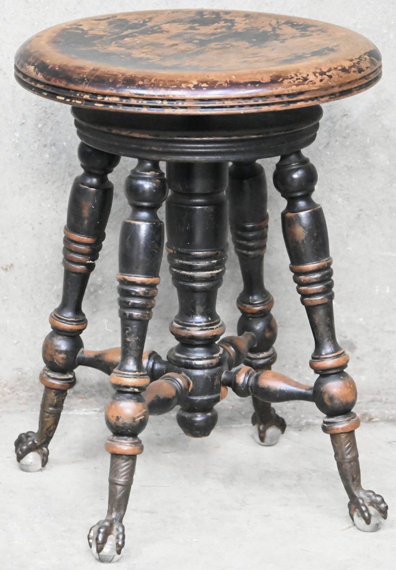 Een houten pianostoel, met rond zitvlak in hoogte verstelbaar. Steunend op bronzen klauwpoten met glazen bollen. Gemerkt “Tonk Chicago New York”.
