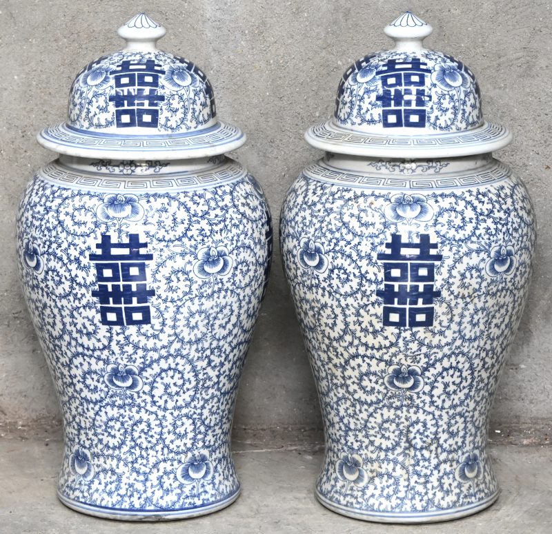 Een paar blauw-wit Chinees porseleinen dekselvazen. Floraal patroon met schrift in het decor.