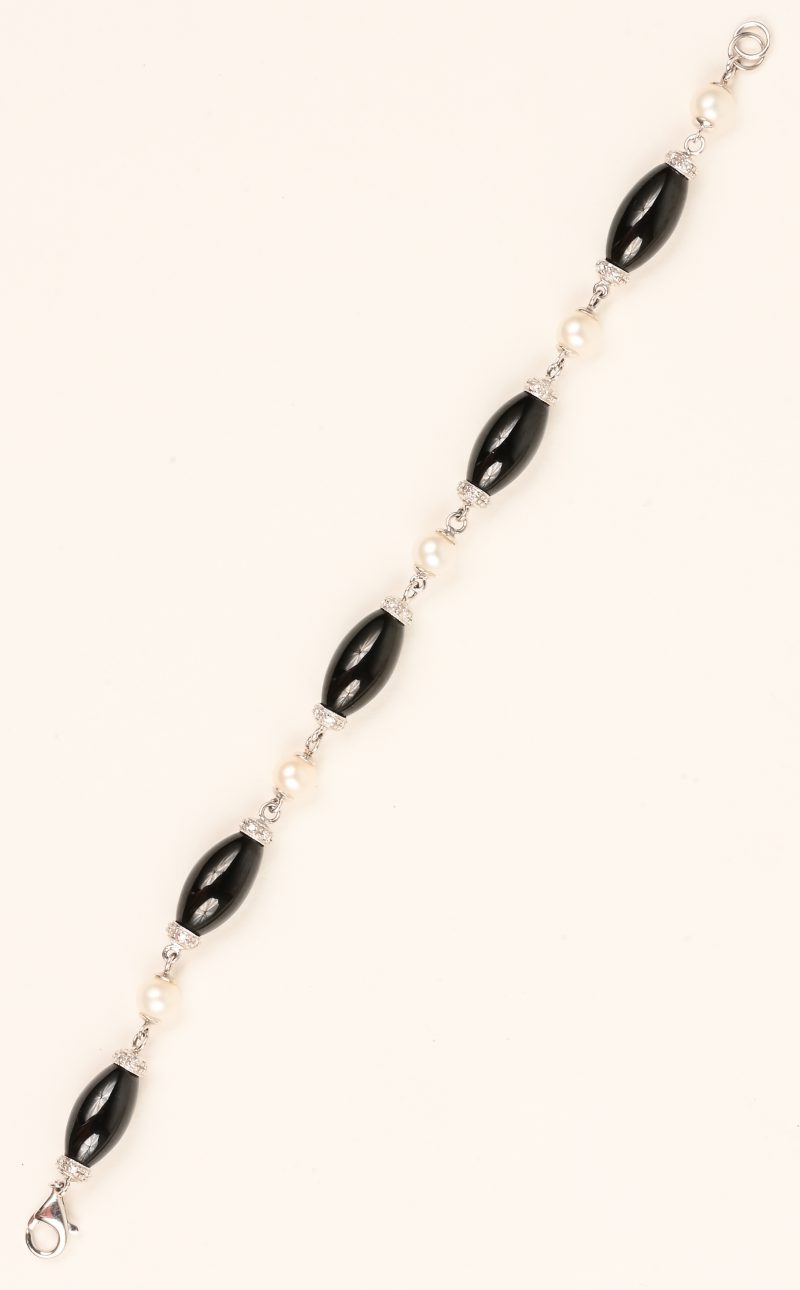 Een 18 karaats wit gouden armband bezet met zwarte half edelstenen, witte parels en diamanten met een gezamenlijk gewicht van ± 0,35 ct.