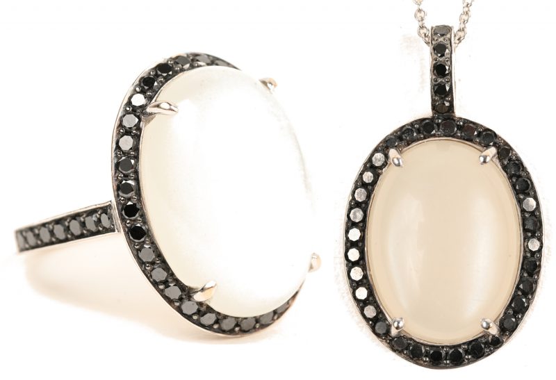 Een 14 karaats witgouden ketting met 18 karaats witgouden hanger en bijpassende ring bezet met zwarte diamanten met een gezamenlijk gewicht van +- 1,30 ct. en twee maanstenen met een gezamenlijk gewicht van +- 20 ct.