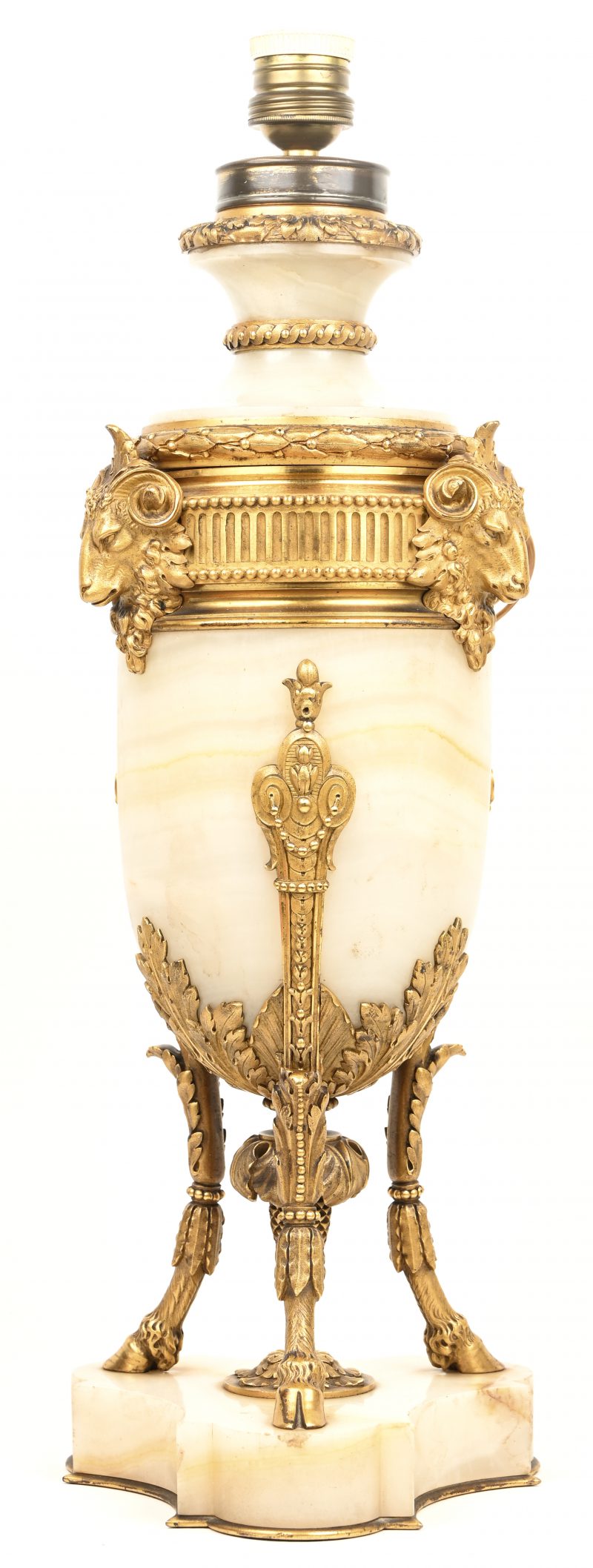 Een rijkelijk versierde lampenvoet in albast en bronzen delen waaronder ramskoppen en poten. Er is kleine schade aan de onyxen voet.