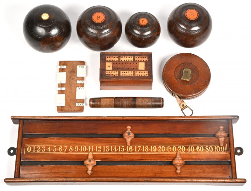 Een lot antieke sport- en spelmaterialen, bestaande uit vier bowls (koersballen), een lintmeter in lederen etui, een kaartenkistje met scoreteller, een kleine puntenteller met benen toetsen en een scorebord.